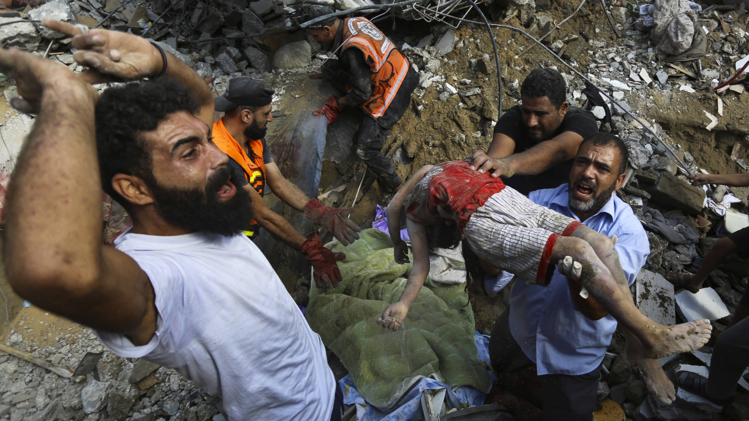 Des Palestiniens portent un enfant retrouvé sans vie sous les décombres d’une maison détruite après des frappes aériennes à Gaza, le 24 octobre 2023 (AP)