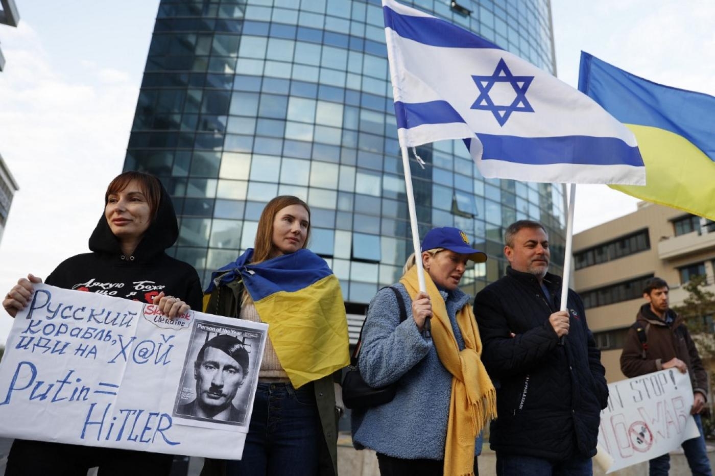 Une manifestante tient une pancarte montrant le président russe Vladimir Poutine en Adolf Hitler lors d’une manifestation devant l’ambassade russe en Israël, le 26 février (AFP)