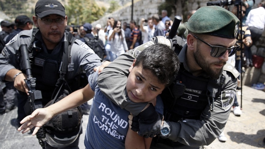 Israeli security forces detain a Palestinian youth during a demonstration outside al-Aqsa mosque in Jerusalem's Old City on 17 July 2017 (AFP)