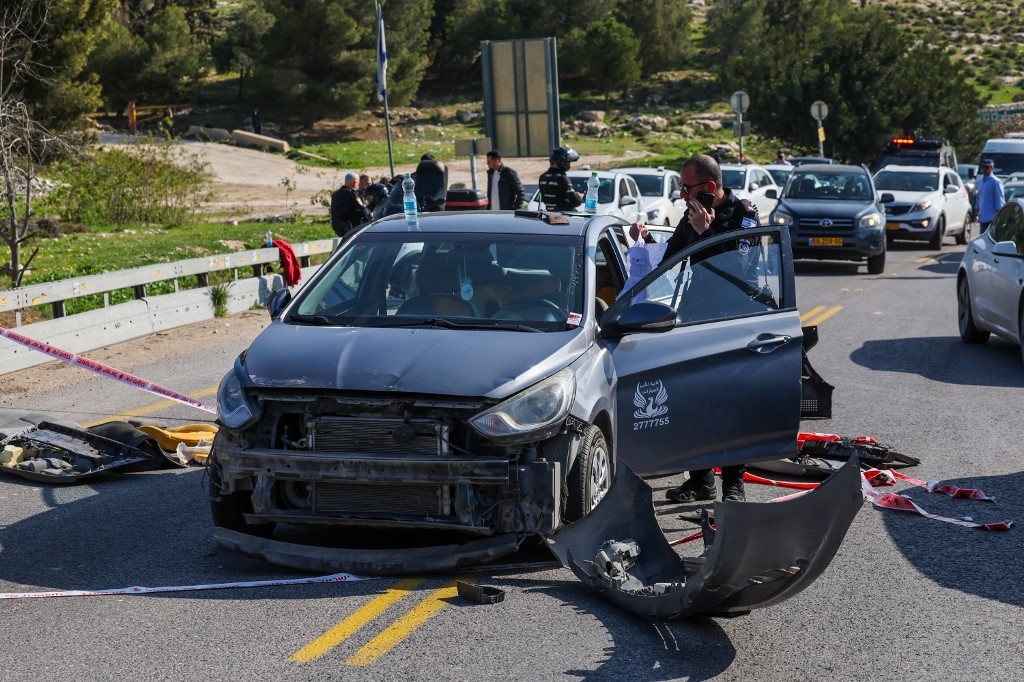 A member of the Israeli security forces inspects a damaged car at the scene of a shooting near the Maale Adumim settlement in East Jerusalem on 22 February 2024 (Ahmad Gharabli/AFP)