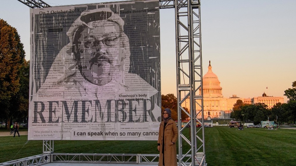Hatice Cengiz, fiancée of Jamal Khashoggi, poses next to a portrait of him in Washington, DC in October 2021 (AFP)