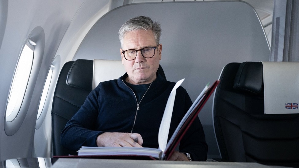 Keir Starmer poses for a photograph as he works whilst travelling on a government aeroplane on 17 November (Stefan Rousseau/AFP)