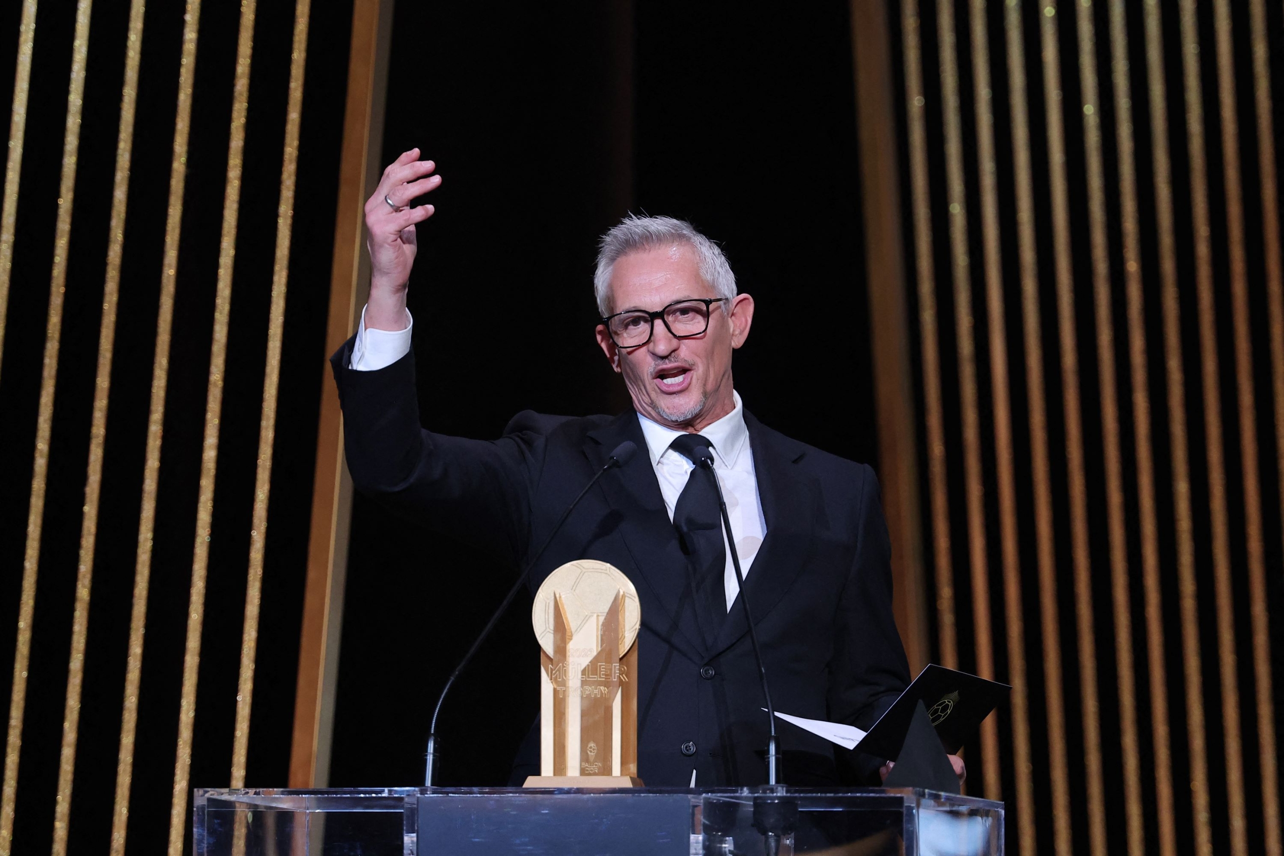 Gary Lineker, former England footballer turned sports TV presenter, gestures on stage with the Gerd Muller Trophy for best striker during the 2023 Ballon d'Or France Football award ceremony at the Theatre du Chatelet in Paris on October 30, 2023 (Franck Fife/AFP)
