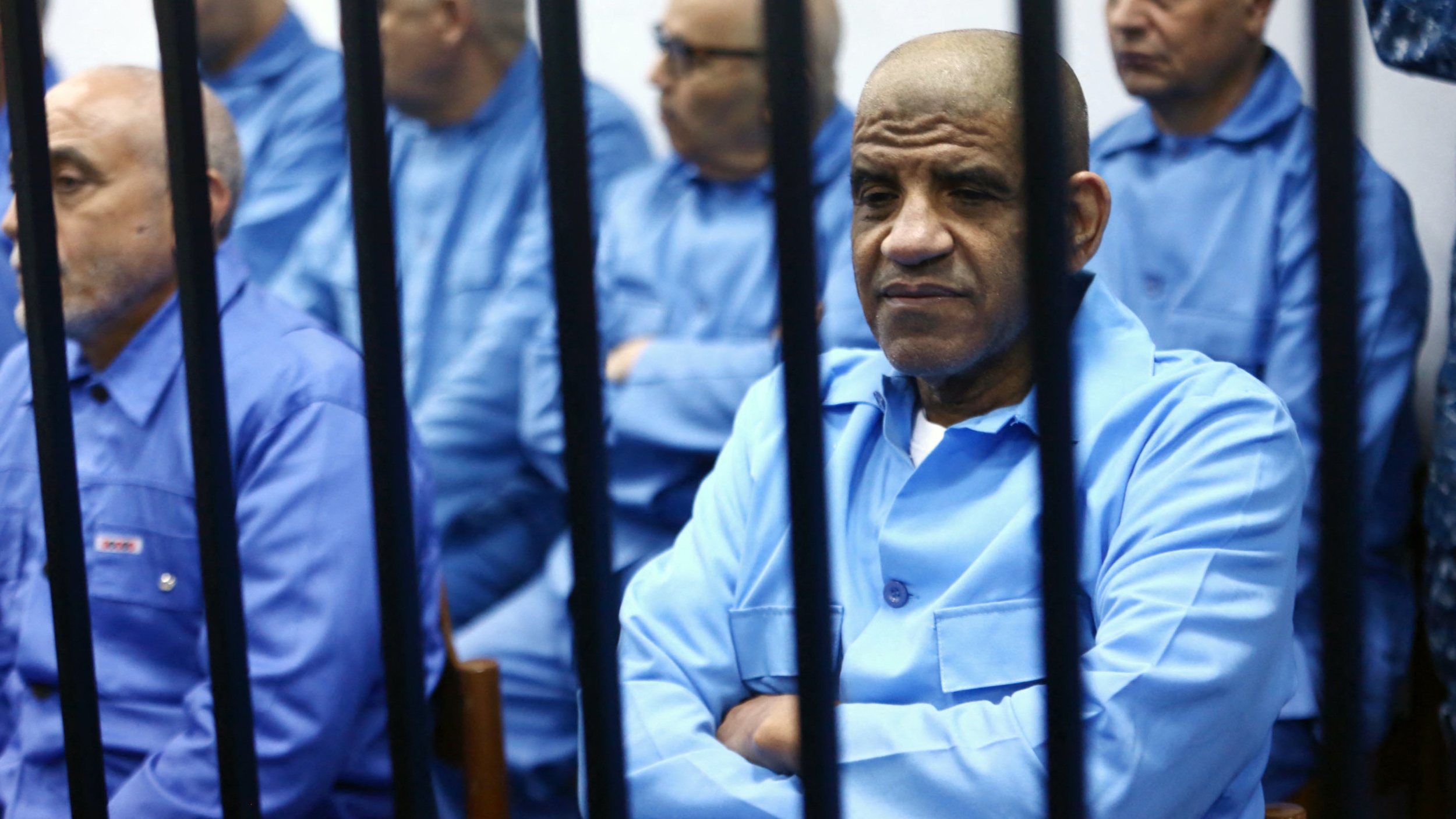 Former Libyan intelligence chief Abdullah al-Senussi (R) sits with other defendants behind the bars during a hearing on 22 February 2015 in a courthouse in Tripoli (AFP)