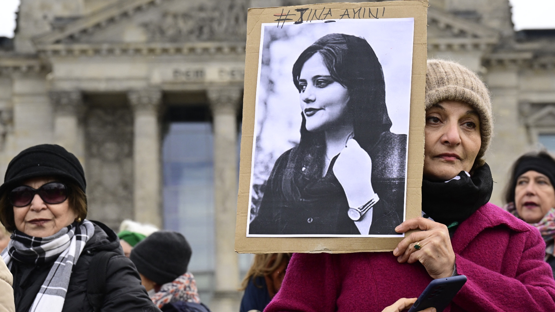 A woman holds a portrait of Mahsa Amini, a young Iranian woman who died after being arrested in Tehran by the Islamic Republic's morality police, during a demonstration in front of the German lower house of parliament on 8 March 2023 (AFP)