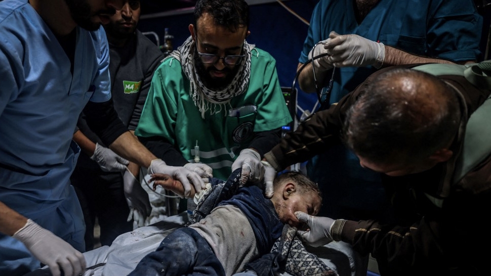 Medics treat a wounded child at Kuwait hospital in Rafah in the southern Gaza Strip following an Israeli strike on 28 December 2023 (Mohammed Abed/AFP)