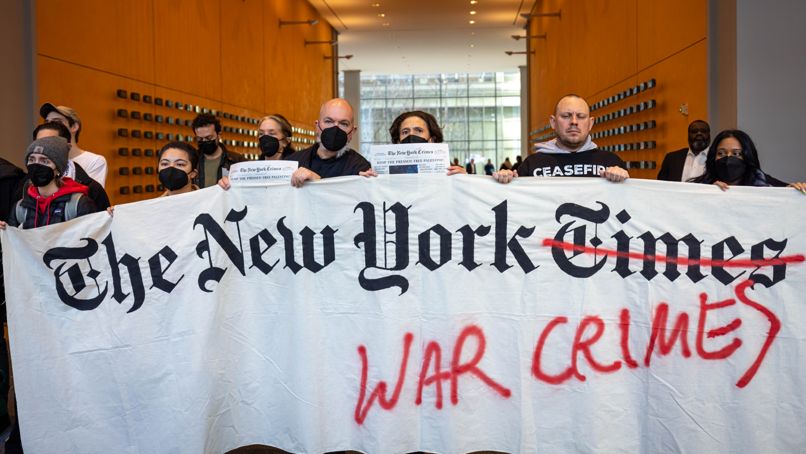 Pro-Palestine protesters hold a banner inside the lobby of The New York Times's offices during an action criticising the newspaper's coverage of Israel's war on Gaza on 14 March in New York City (Michael Nigro/Sipa USA via Reuters)