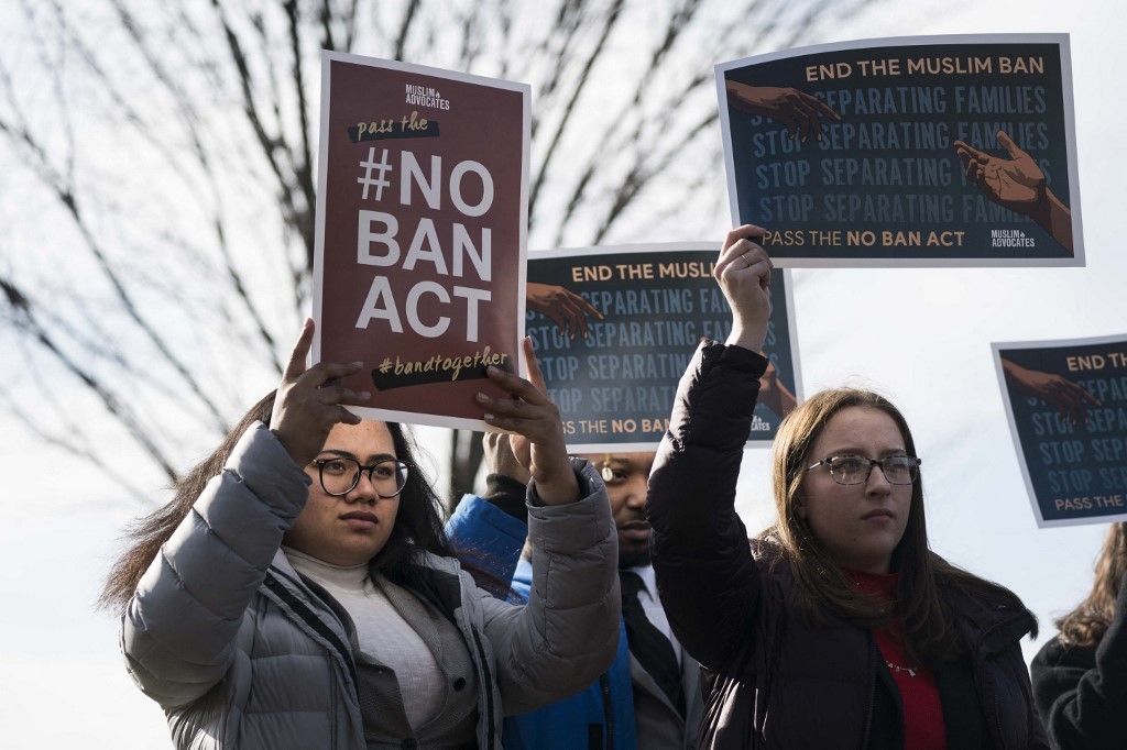 People hold signs showing their support for the No Ban Act during a news conference outside of the US Capitol on 27 January 2020 (AFP/File photo)