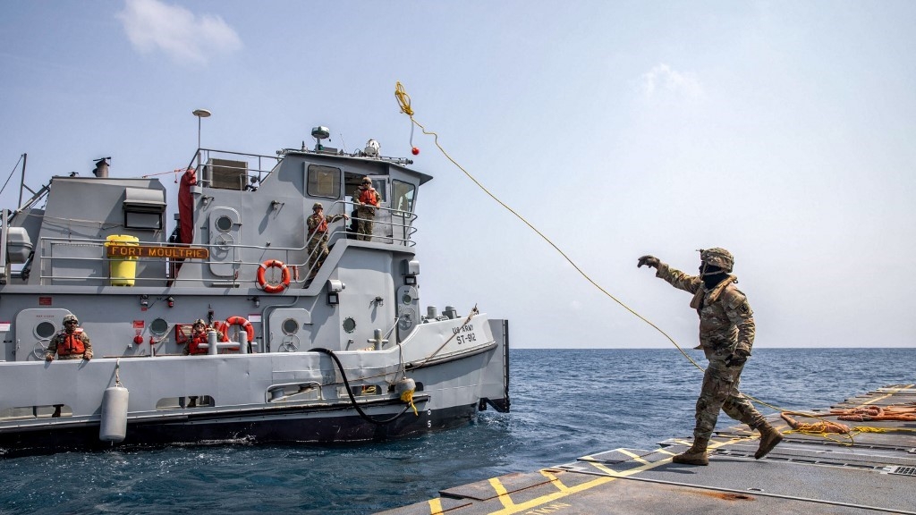 A US soldier of the 7th Transportation Brigade tosses a line to an Army tug vessel from the floating pier in Gaza on 1 May 2024 (Centcom/AFP)