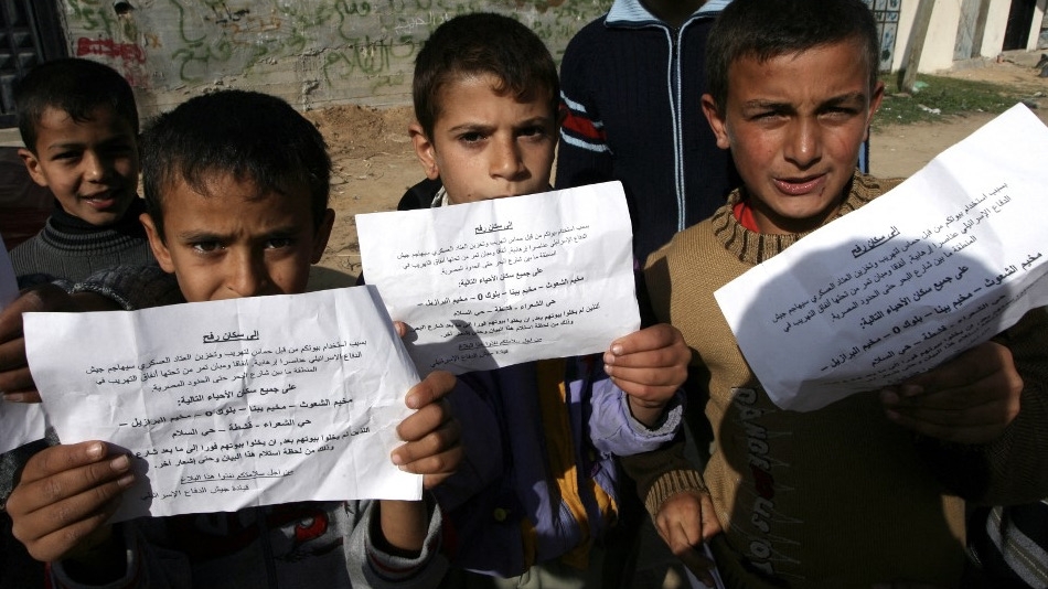 Palestinian boys with leaflets dropped by Israel over the Gaza Strip warning residents it was about to escalate its military campaign, 11 January 2009 (Said Khatib/AFP)