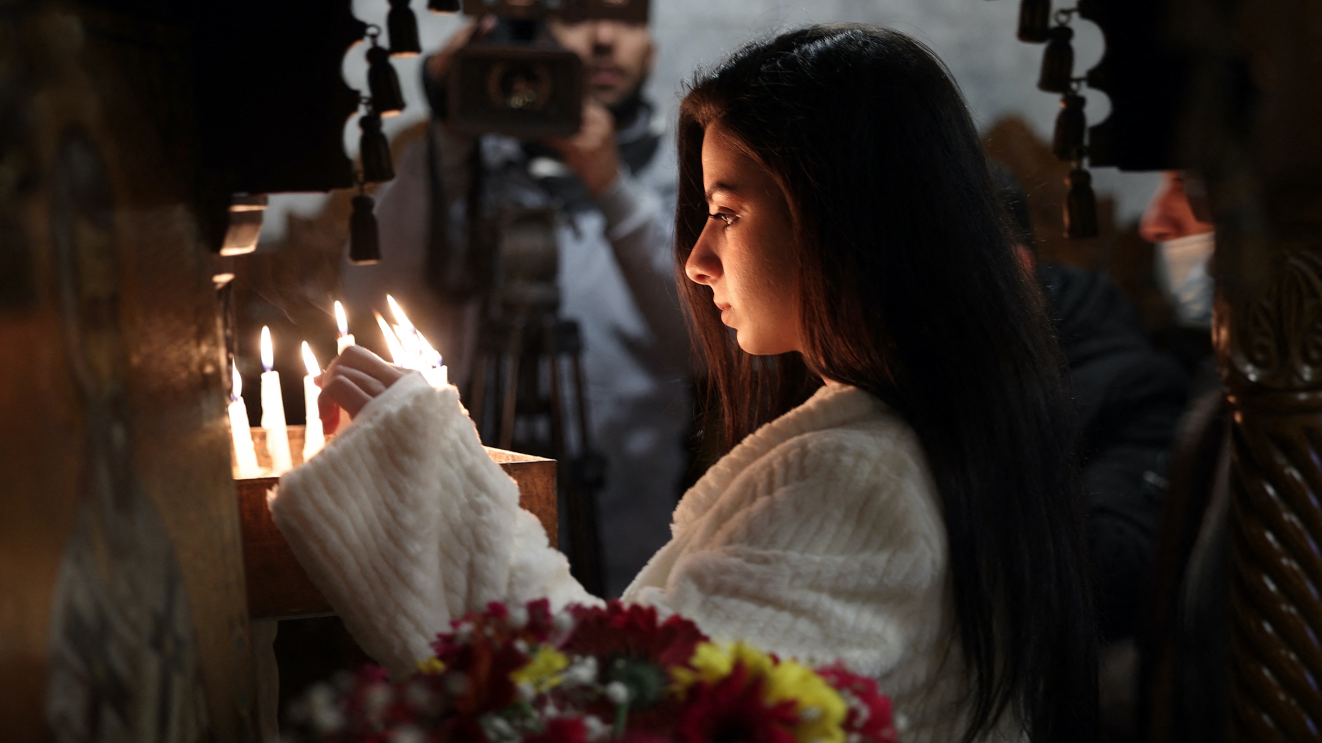 A Palestinian worshipper lights a candle during a Christian Orthodox Christmas mass at the Saint Porphyrios Greek Orthodox church in Gaza City on 7 January 2022 (AFP)