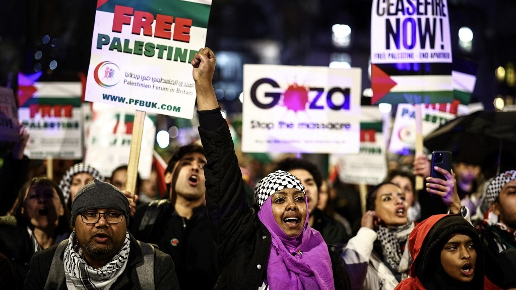 Pro-Palestinian demonstrators wave Palestinian flags and hold placards as they protest in Parliament Square in London on 21 February 2024 (Henry Nicholls/AFP)