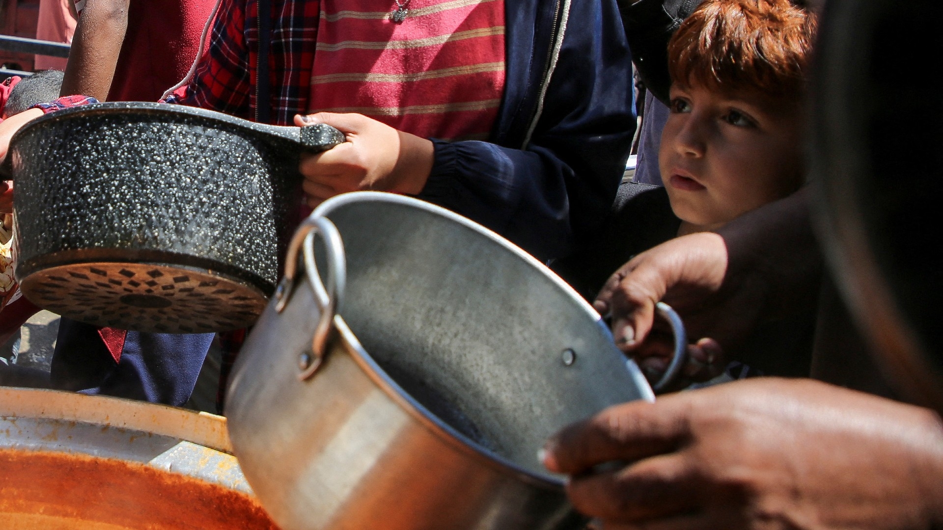 Palestinians gather to receive food cooked by a charity kitchen, amid shortages of aid supplies, after Israeli forces launched a ground and air operation in the eastern part of Rafah, on 8 May (Reuters)
