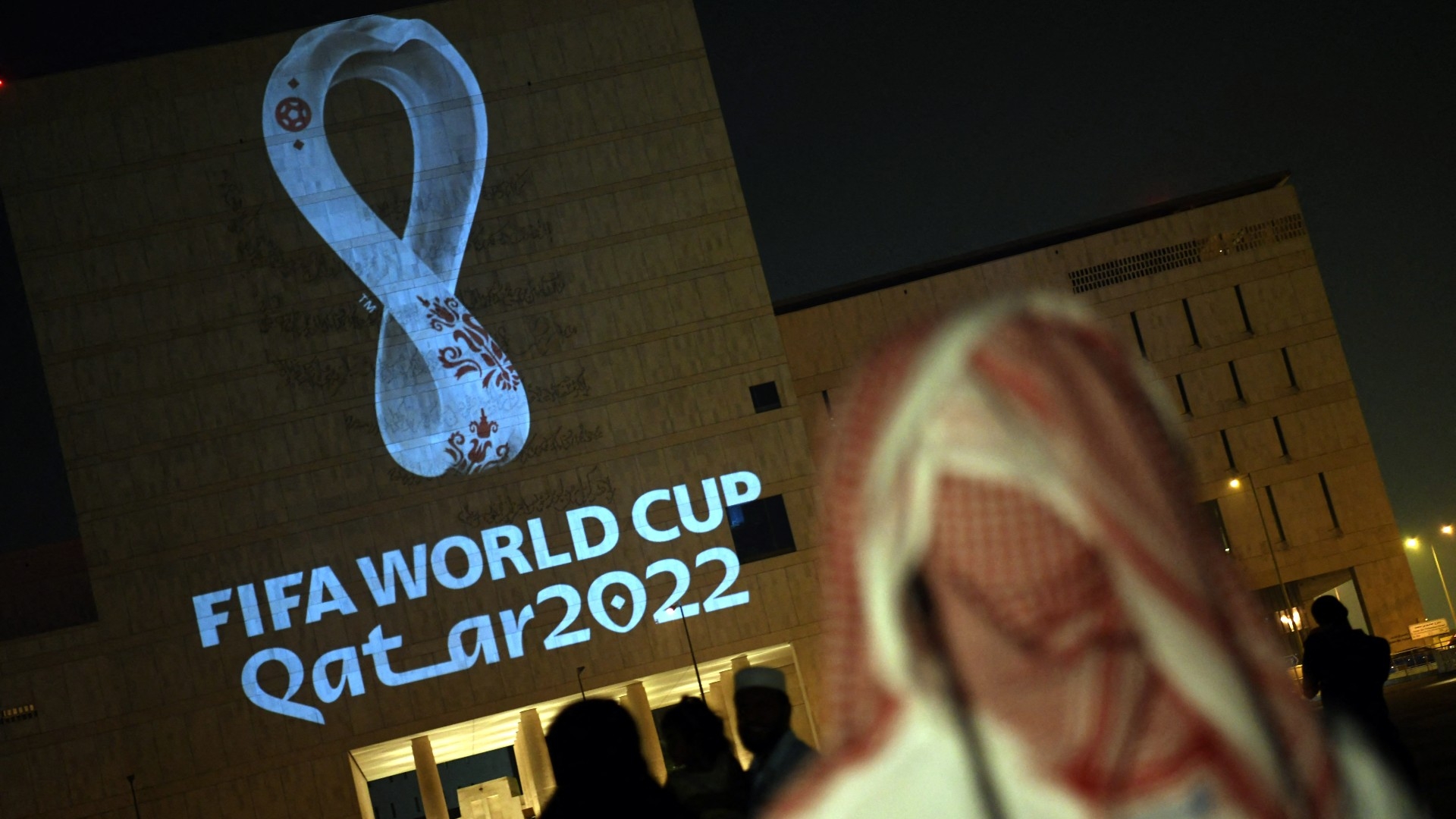 People gather at Doha's traditional Souq Waqif market as the official logo of Fifa World Cup Qatar 2022 is projected on the front of a building, 3 September 2019 (AFP)