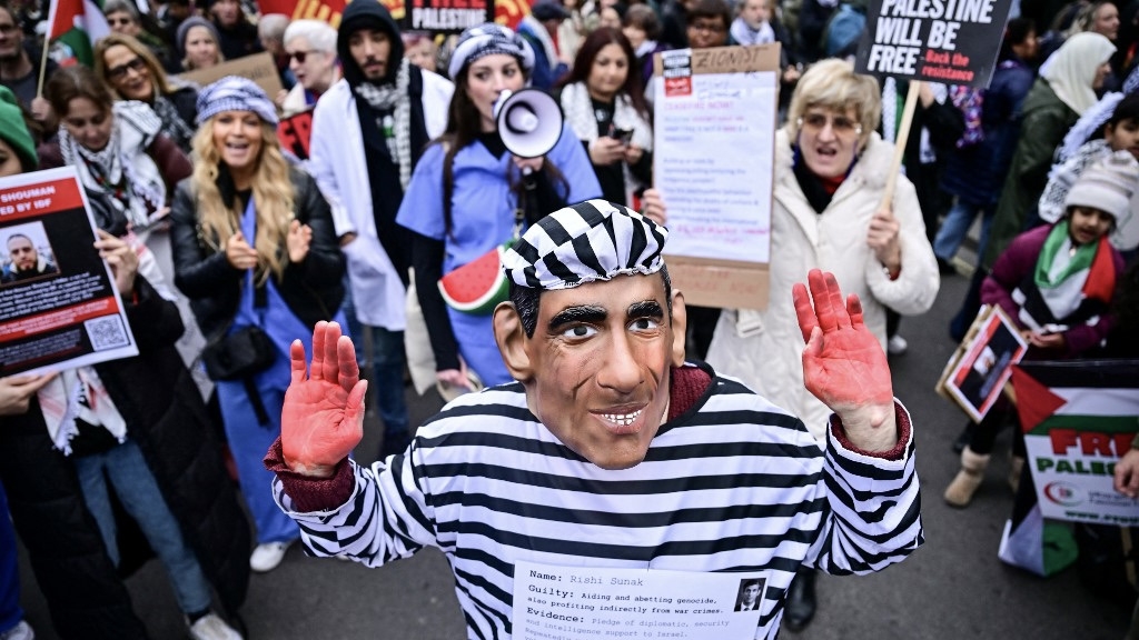 A demonstrator wearing a mask depicting Britain's Prime Minister Rishi Sunak and dressed in a prisoner uniform takes part in a march for Palestine in London on 3 February 2024 (Ben Stansall/AFP)