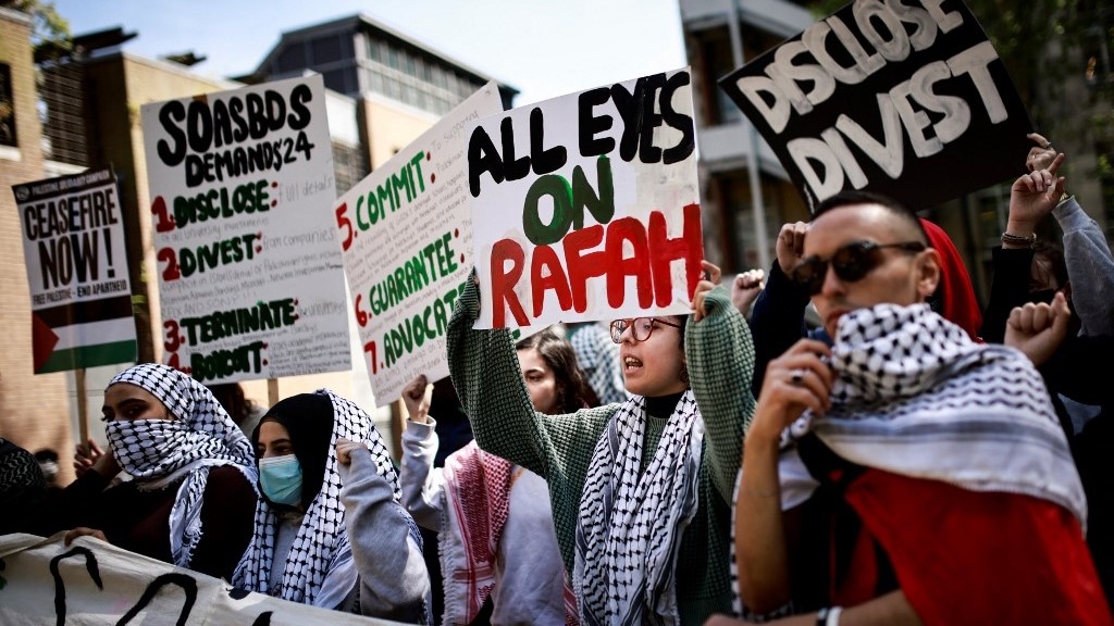 Students hold placards and chant slogans during a pro-Palestinian camp set up on the campus of the School of Oriental and African Studies (Soas) in London on 8 May 2024 (AFP)