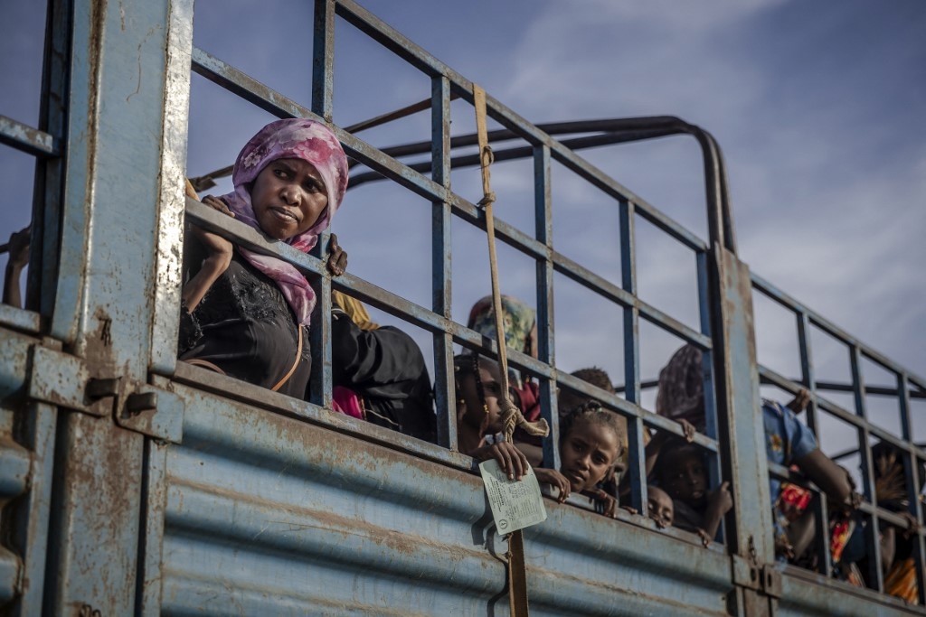 A Sudanese woman who has fled from the war in Sudan looks on from a truck arriving at a transit centre for refugees in Renk on 13 February (AFP/Luis Tato)