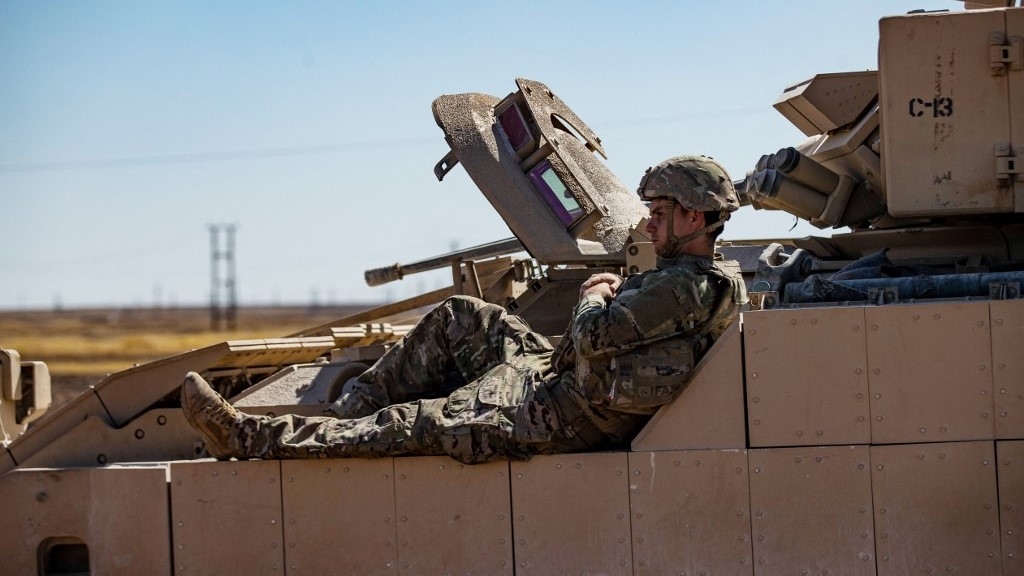 A US soldier rests on a tank as troops patrol oil fields near Syria's northeastern border with Turkey in Qahtaniyah in the far northeast corner of Hasakah province on September 3 2024 (Delil Souleiman/AFP)