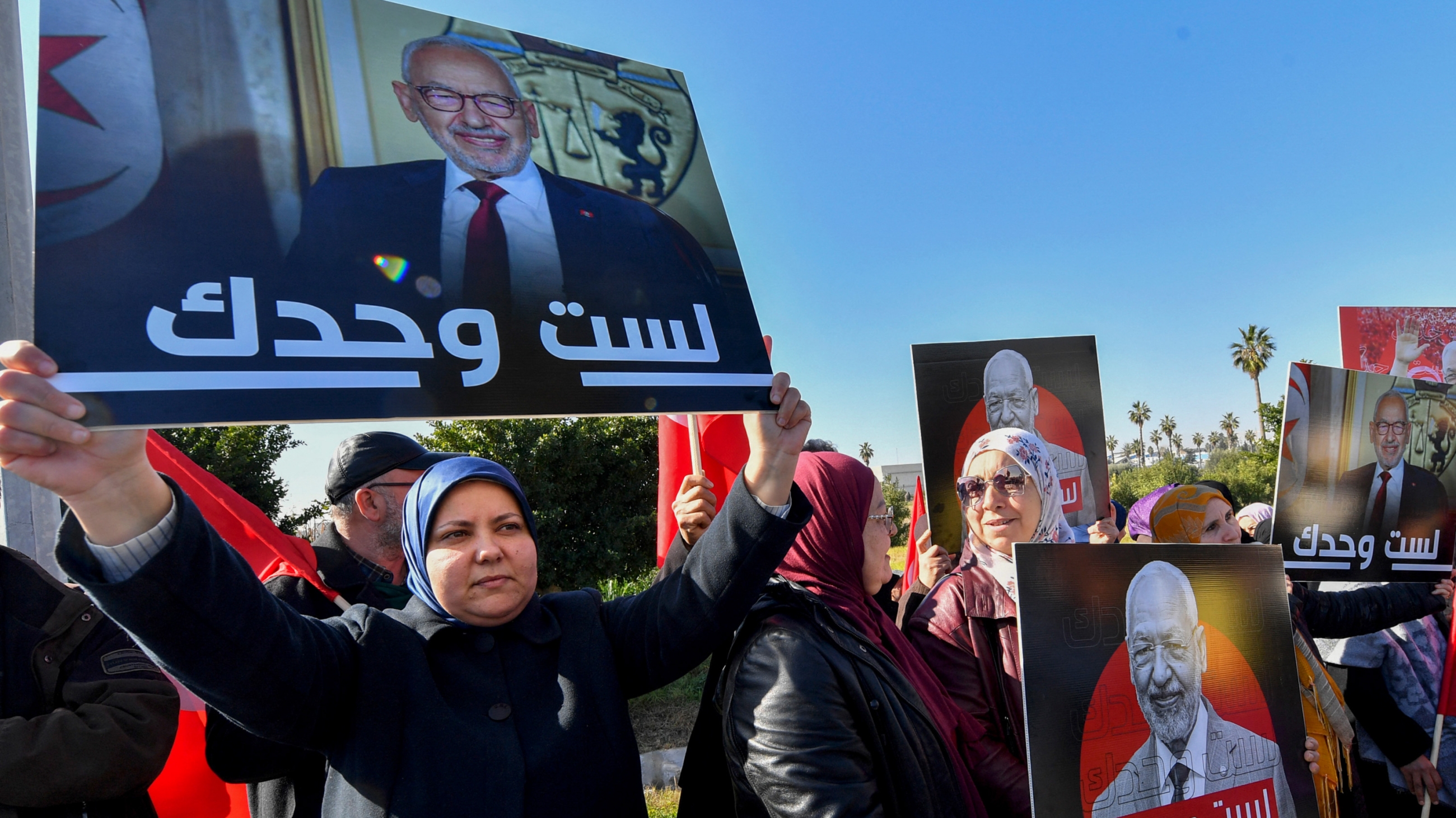 Supporters of the Ennahda leader Rached Ghannouchi express their support as he arrives at a police station in Tunis, 21 February 2023 (AFP)