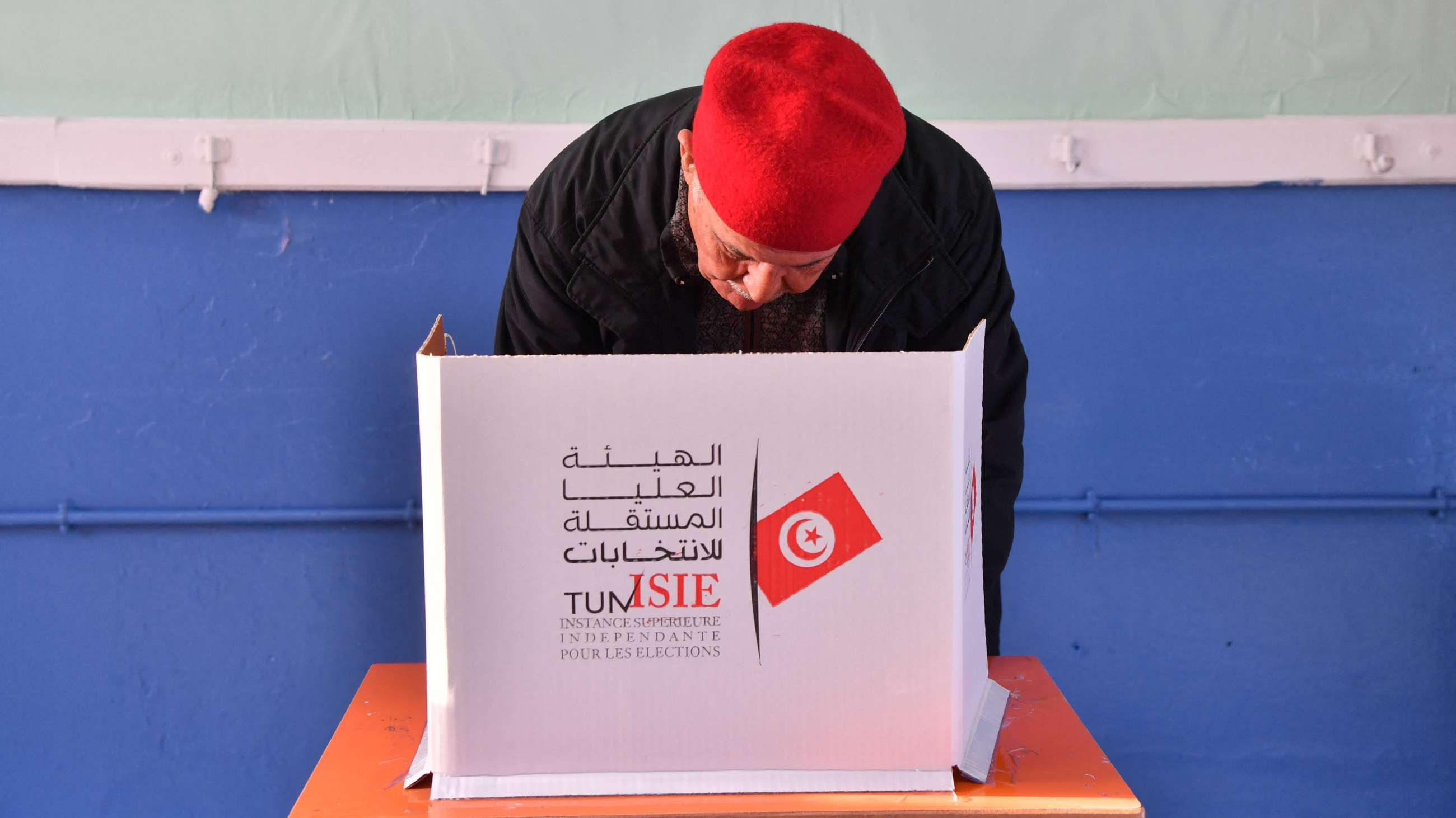 A photo taken on 17 December 2022 shows a Tunisian voter casting his ballot at a polling station in Mnihla district outside Tunis during the parliamentary election (AFP)