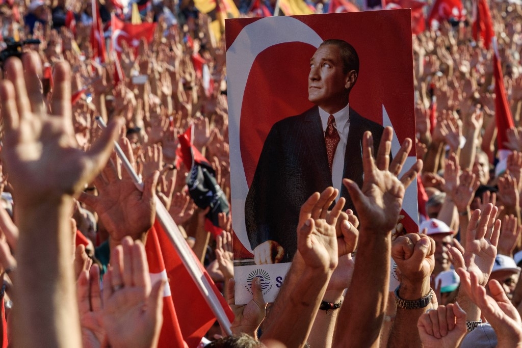 Demonstrators rise their hands and hold a potrait picture of Mustafa Kemal Ataturk, founder of modern Turkey, as they gather at Taksim Square in Istanbul on July 24, 2016 (AFP)