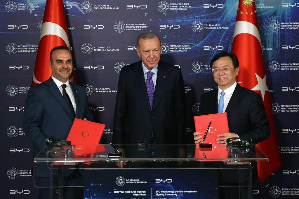 Turkish President Recep Tayyip Erdogan (C), Wang Chuanfu (L), chairman and CEO of Chinese conglomerate manufacturing company BYD and Turkish Minister of Industry and Technology Mehmet Fatih Kacir (R) taking part in a signing ceremony in Istanbul on 8 July 2024 (Handout)