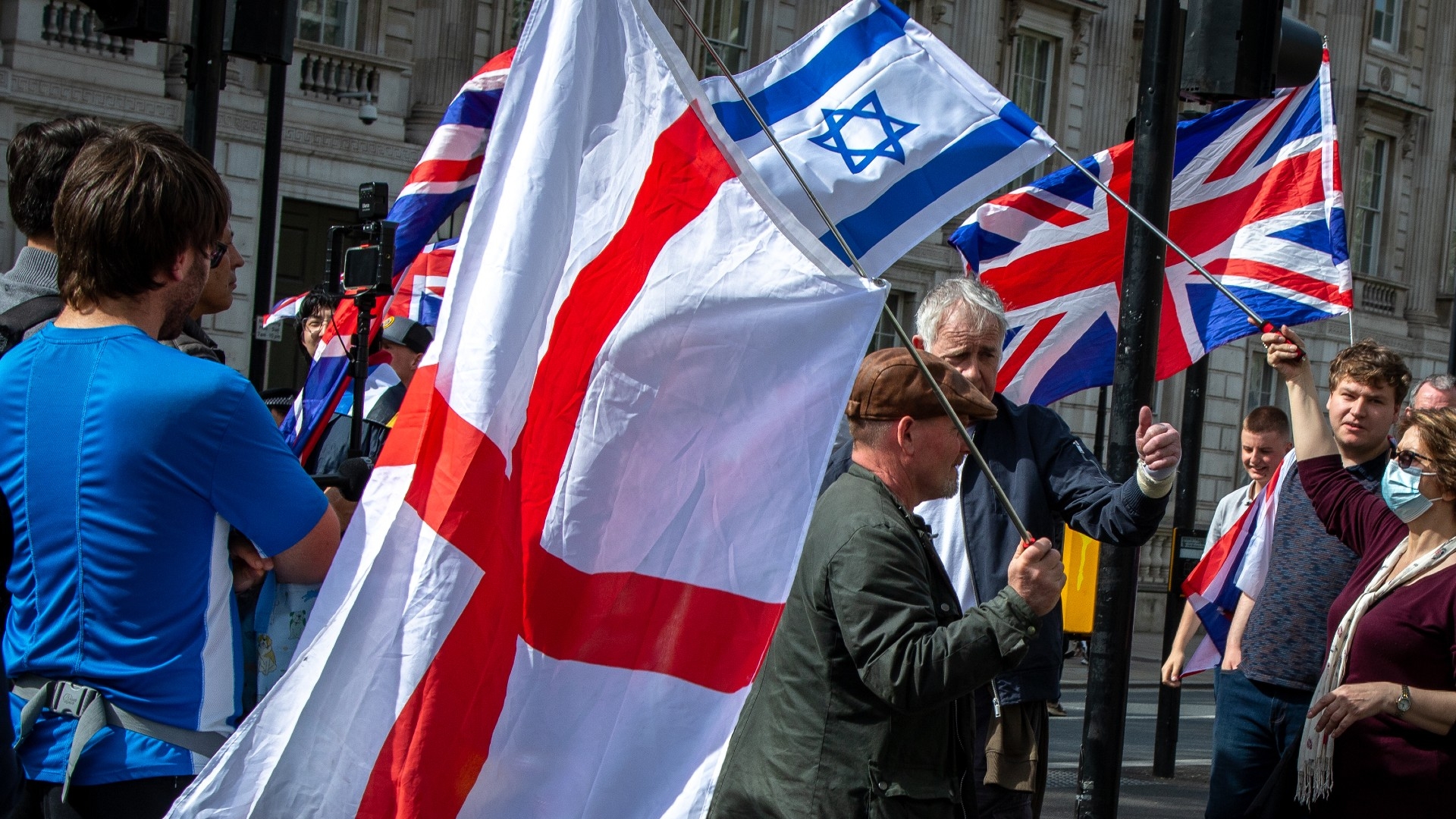 Pro-Israel activists hold flags as protesters marching to Parliament Square in London called for a permanent ceasefire and for the  on the UK government to stop arming Israel and call for a permanent ceasefire in London on 13 April 2024 (Reuters)