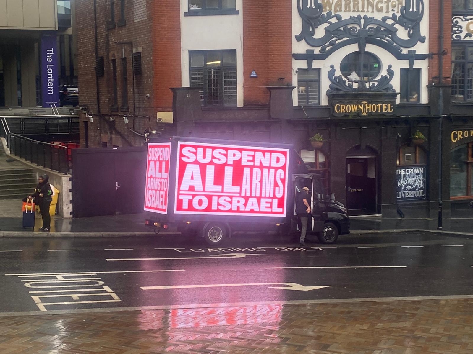 A van displaying a poster reading 'Suspend all arms sales to Israel' parks outside the Labour conference in Liverpool (Dania Akkad)