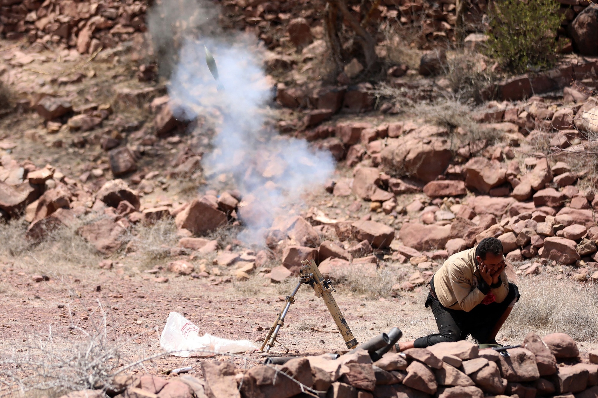 A fighter loyal to Yemen's Saudi-backed government launches a mortar during clashes with Houthis near Taiz