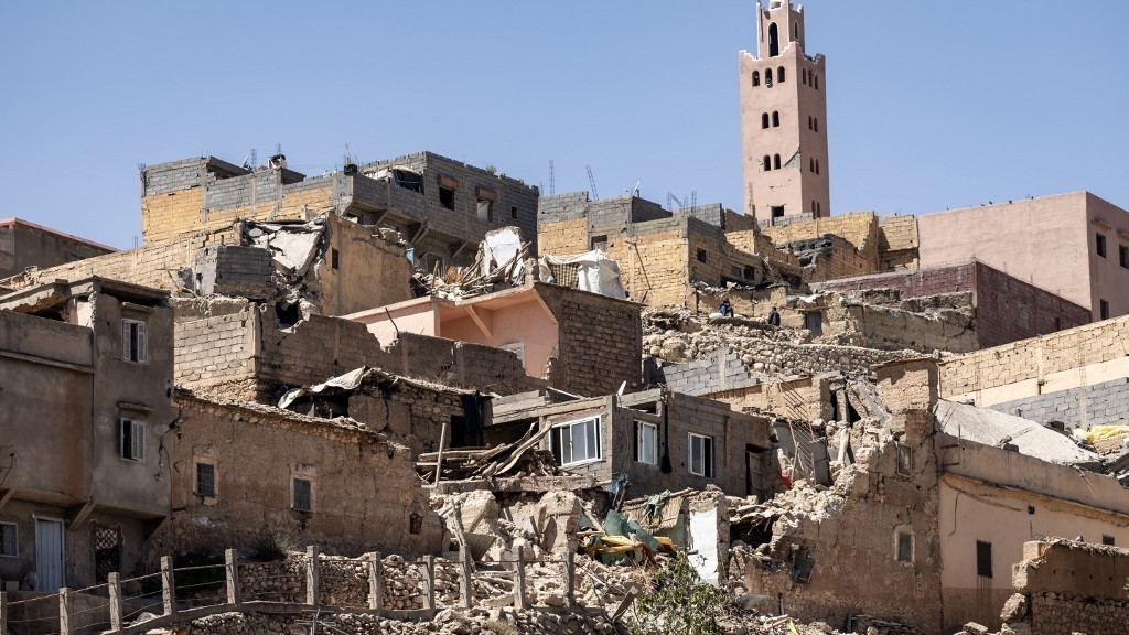 The minaret of a mosque stands behind damaged or destroyed houses following an earthquake in Moulay Brahim, Al-Haouz province, on September 9, 2023 (AFP)