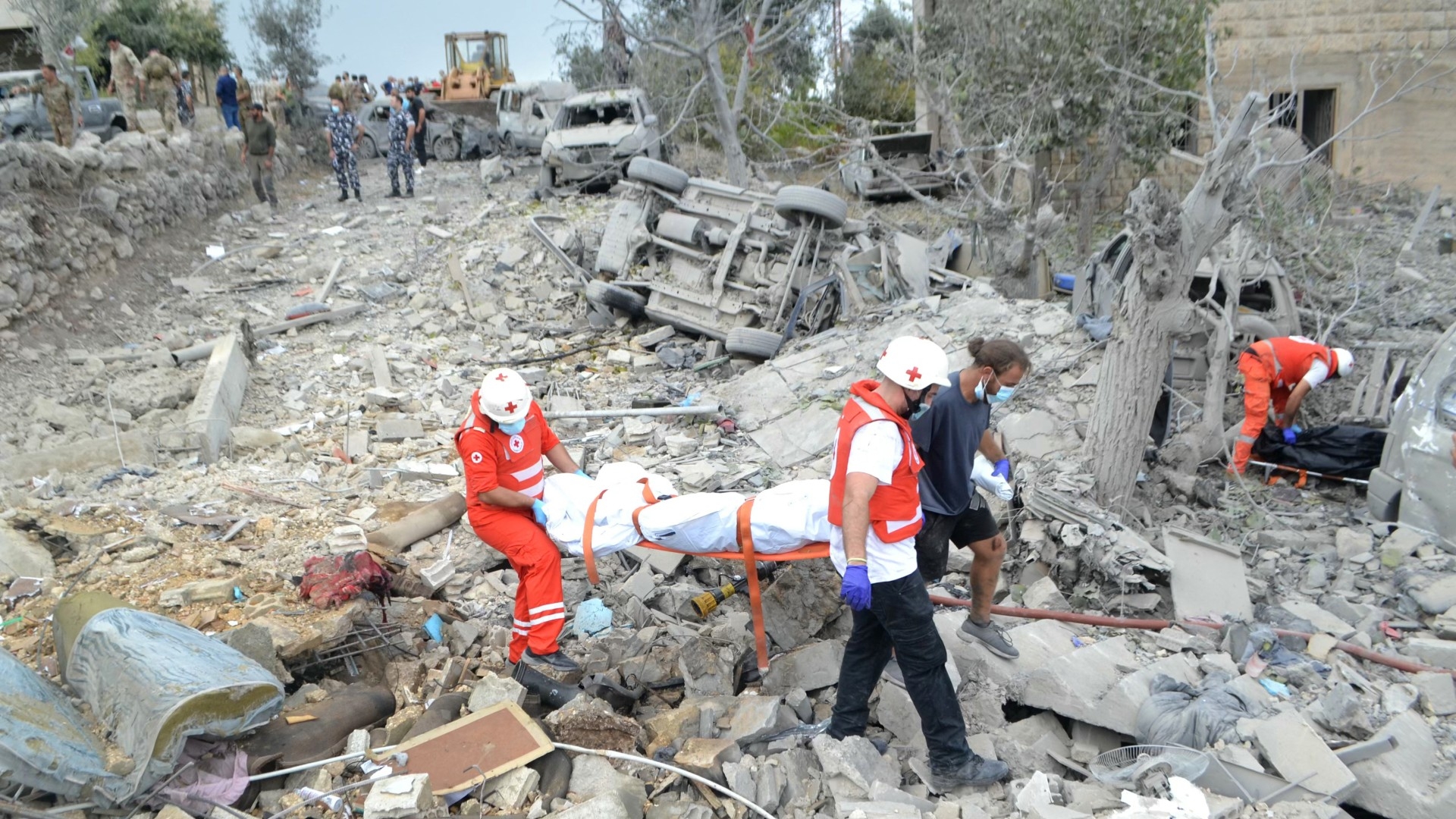 Paramedics with the Lebanese Red Cross transport a body unearthed from the rubble at the site of an Israeli air strike that targeted the northern Lebanese village of Aito on 14 October 2024 (AFP/Fathi Al-Masri)