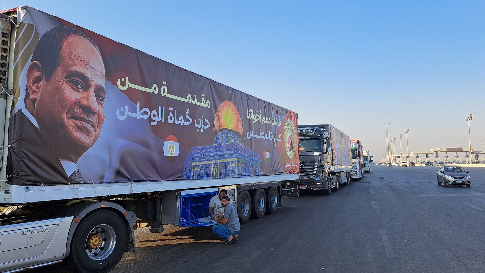 A convoy of trucks carrying aid supplies for Gaza from Egypt waits on the main Ismailia desert road on 16 October (AFP/Khaled Desouki)