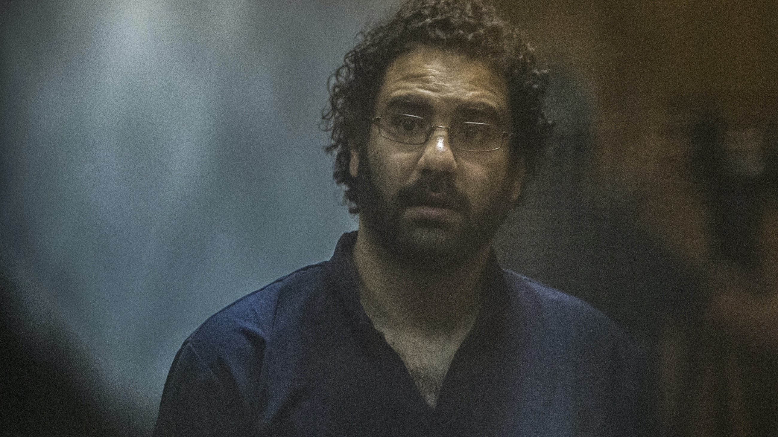Egyptian activist Alaa Abd el-Fattah looks on from behind the defendant's cage during his trial in Cairo on 23 May 2015 (AFP)