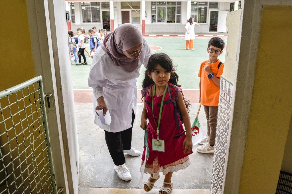 Une enseignante accueille une élève, dans une école d’Alger, le 19 septembre, jour de rentrée (AFP)