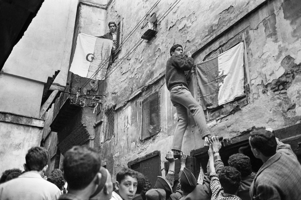 De jeunes Algériens accrochent un drapeau national sur un mur de la Casbah d’Alger, le 6 juillet 1962, au lendemain de la proclamation de l’indépendance (AFP)
