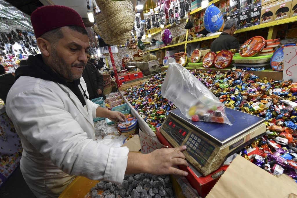Un vendeur pèse une commande de bonbons dans sa boutique du centre-ville de Blida, au sud d’Alger, le 11 janvier 2024, alors que les gens se préparent à célébrer le Nouvel An amazigh (AFP)