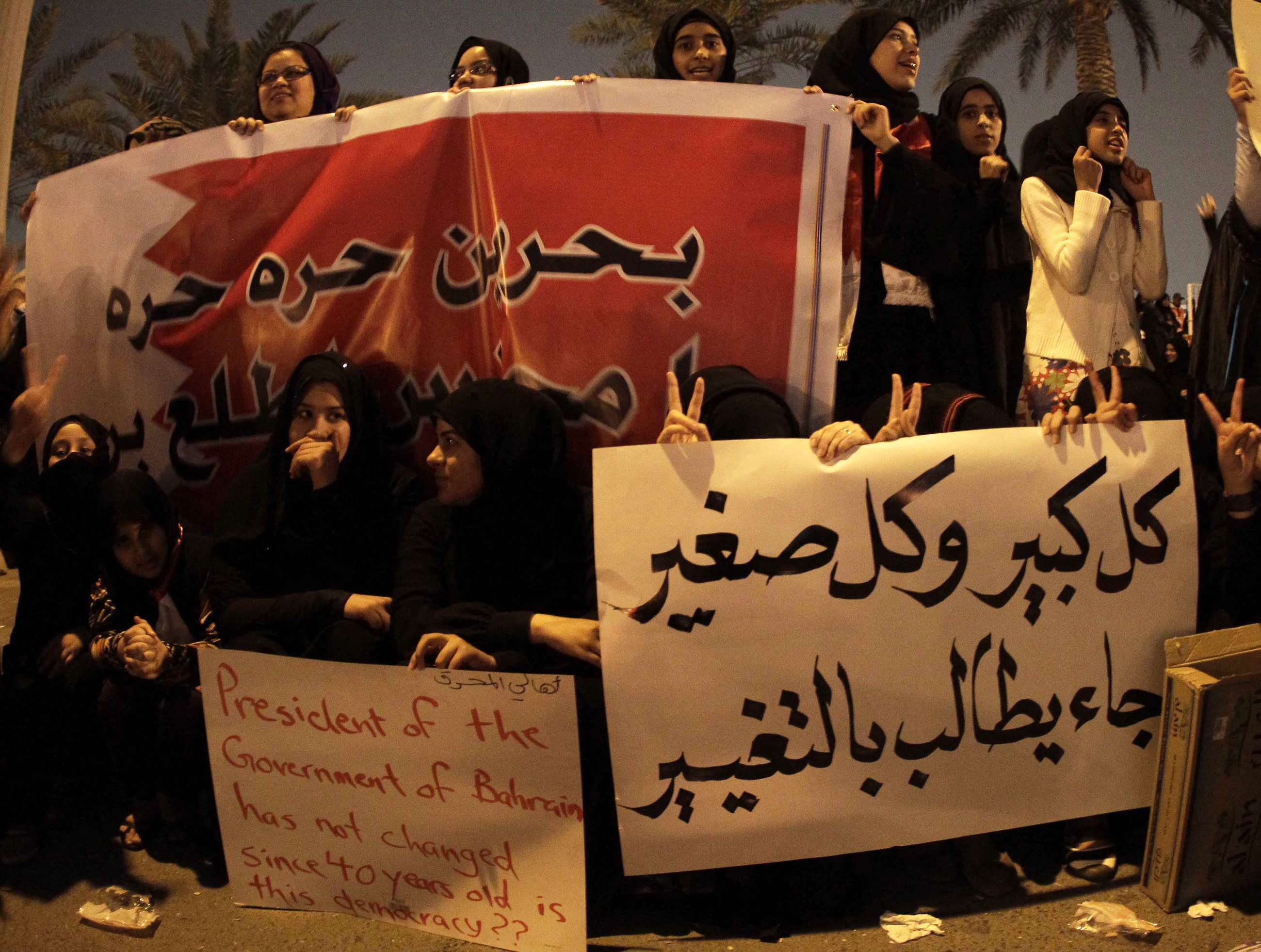 Bahraini anti-government protesters hold signs calling for freedom and change as they gather at Pearl Square in Manama on 16 February 2011.