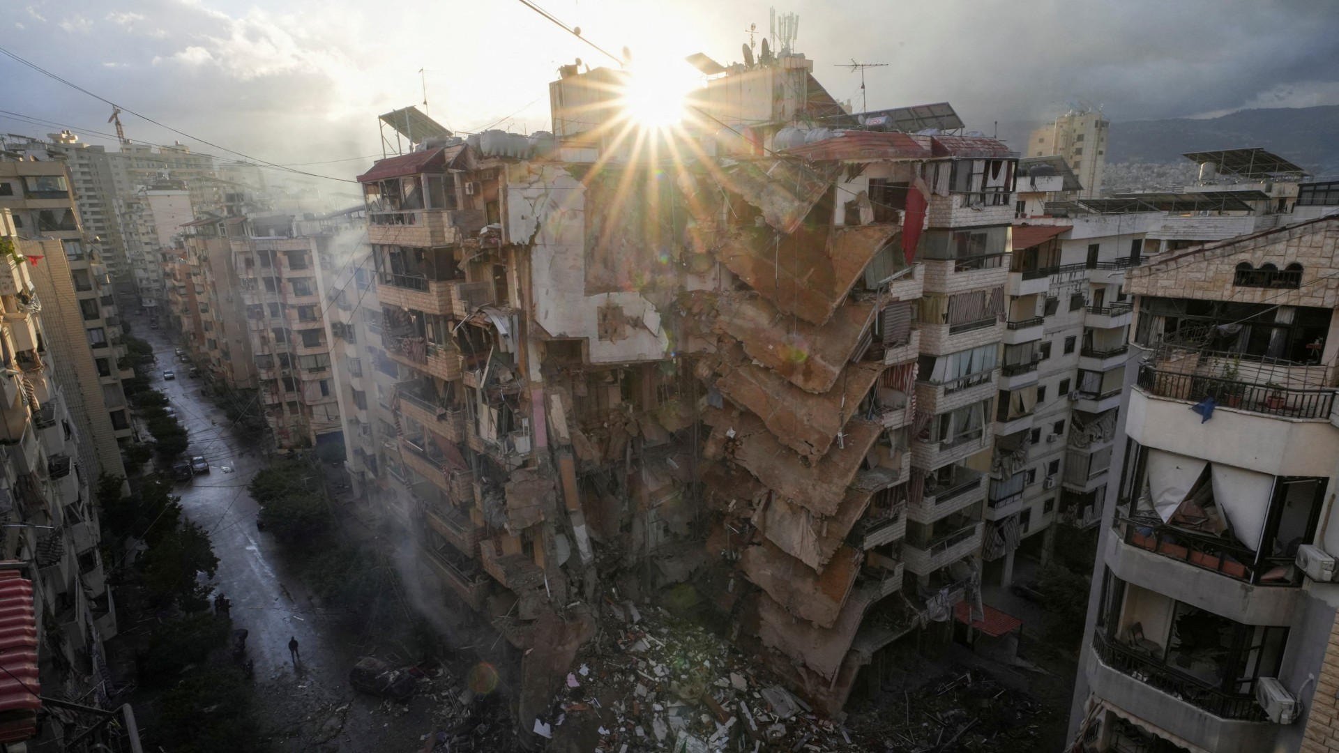 People walk past damaged buildings in the aftermath of Israeli strikes on Beirut's southern suburbs 25 November (Reuters/Mohammed Yassin)