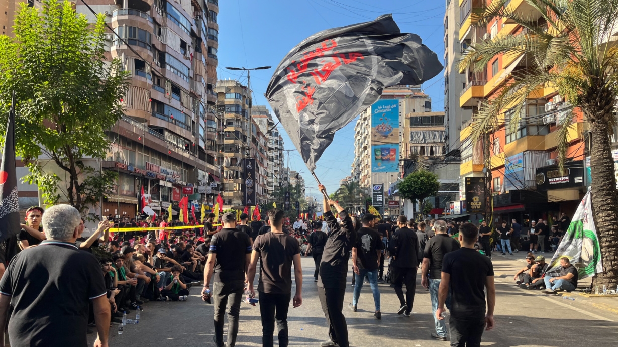 A man waves a black flag during the Ashura commemoration in a southern suburb of Beirut, Lebanon, on 17 July 2024 (Nader Durgham/MEE)