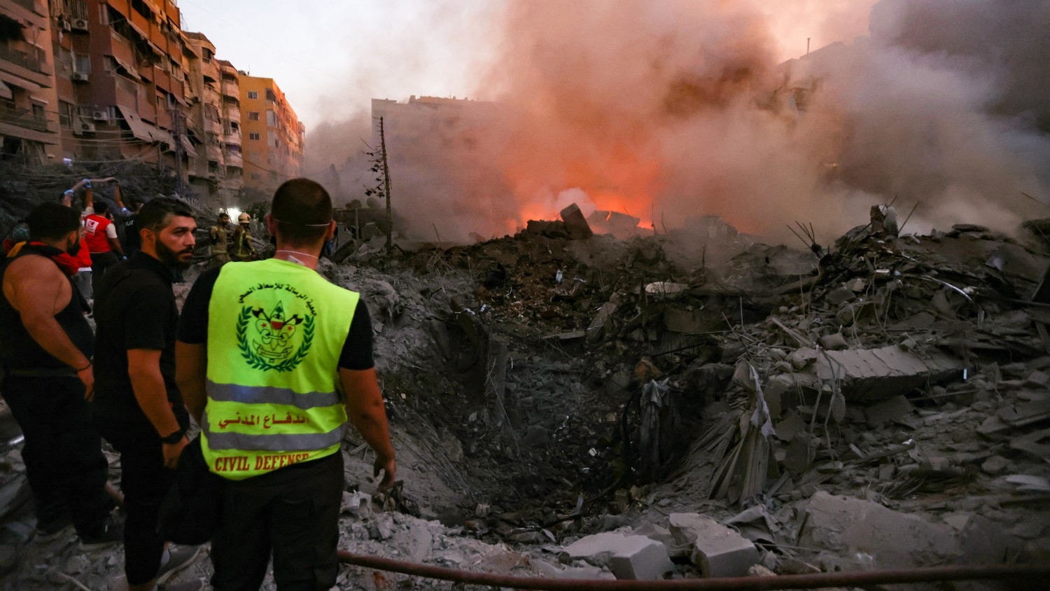 People and rescuers gather near the smouldering rubble of a building destroyed in an Israeli air strike in the Haret Hreik neighbourhood of Beirut's southern suburbs on 27 September 2024.