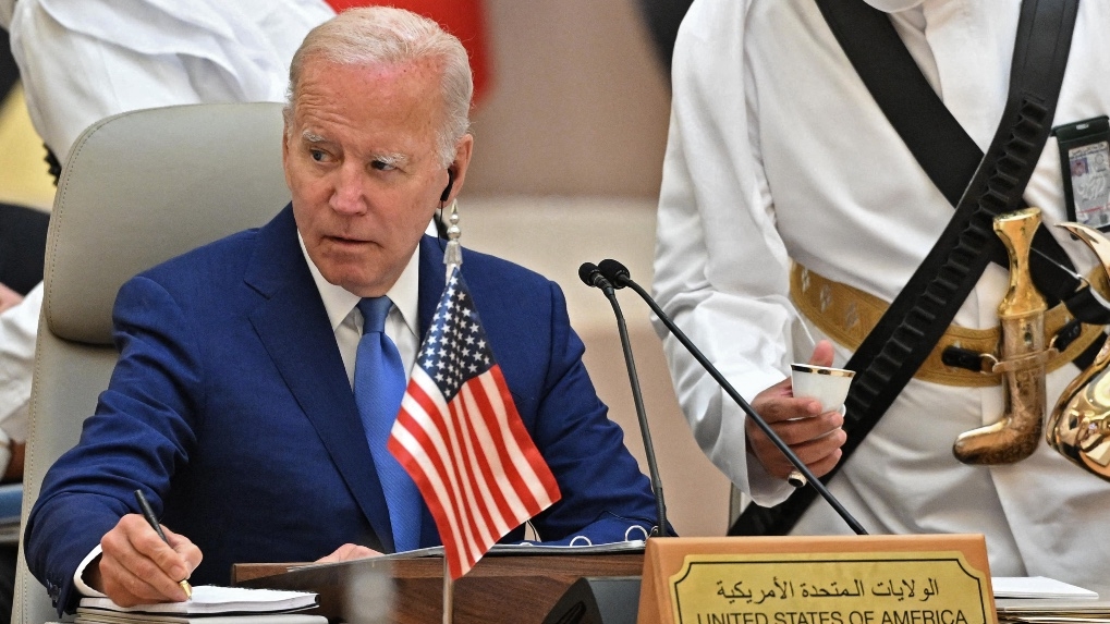 US President Joe Biden takes notes while an usher serves coffee during the Jeddah Security and Development Summit in Jeddah, Saudi Arabia on 16 July 2022.