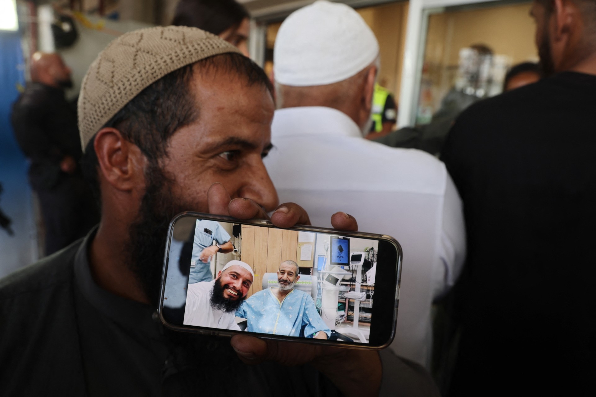 The brother of freed captive Kaid Alkadi shows a mobile phone picture of him with another brother, after his arrival for a check-up at the Soroka Medical Center in Beersheva in southern Israel on 27 August 2024 (AFP/Menahem Kahana)