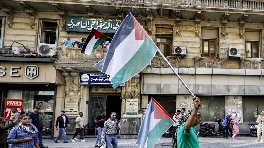 A man waves a Palestinian flag while marching past the headquarters of the Arab Democratic Nasserist Party along Talaat Harb Street in the centre of Cairo on 20 October 2023 (AFP)