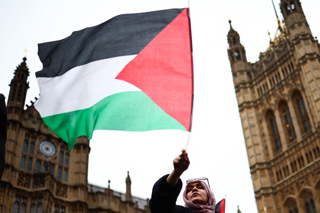 A demonstrator waves a Palestinian flag during a protest in Parliament Square, London, 21 February 2024 (Henry Nicholls/AFP)