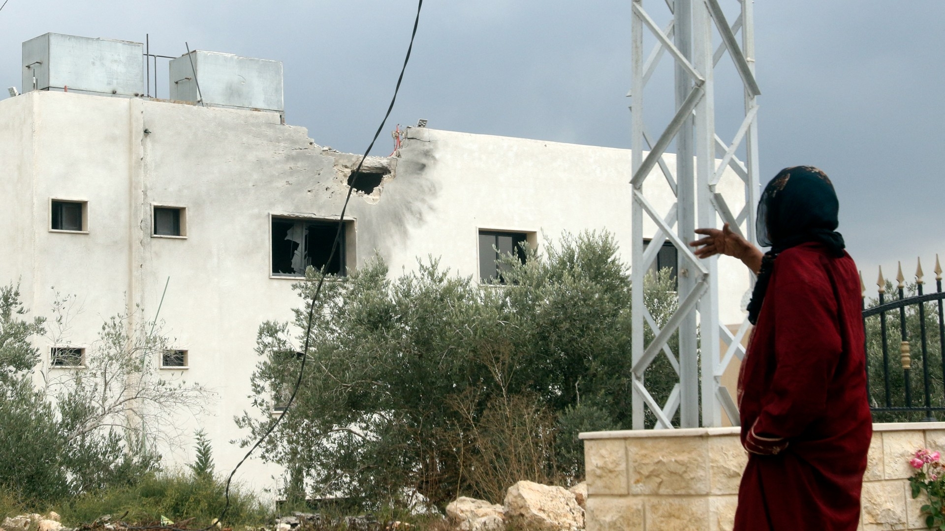 A woman gestures outside a building shelled by Israeli forces on the outskirts of the southern Lebanese border village of Dhayra on 11 October, 2023 (Mahmoud Zayyat/AFP)