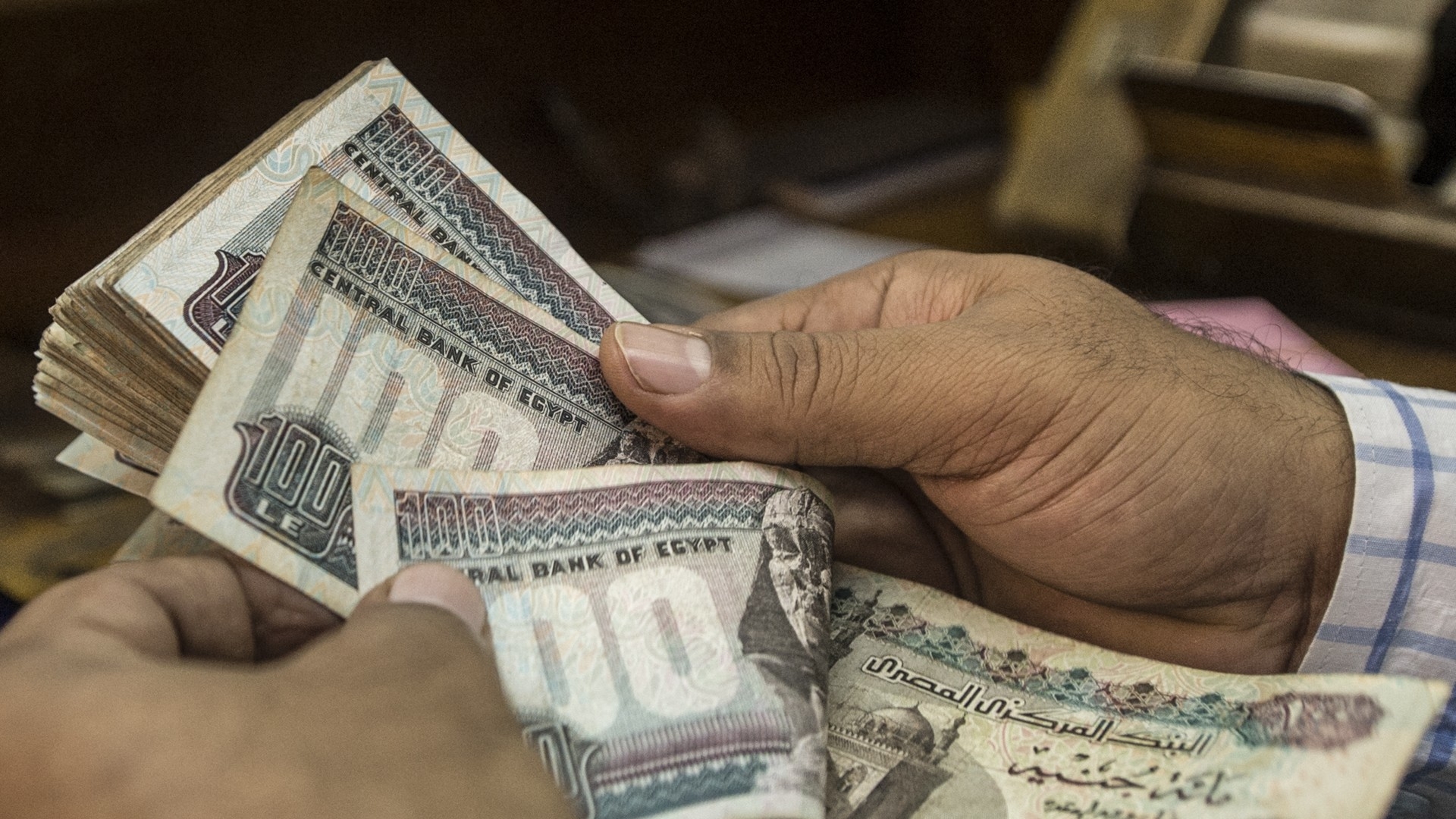 A man counts Egyptian pounds at a currency exchange shop in Cairo, on 3 November 2016 (AFP)