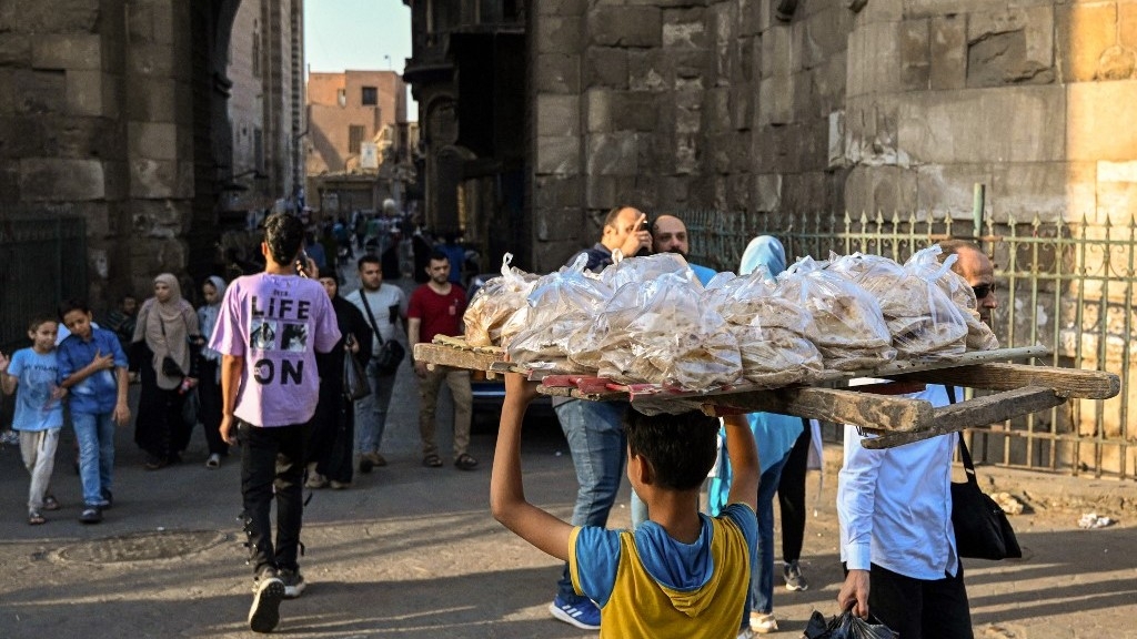 A young boy delivers freshly-baked bread in the al-Darb al-Ahmar district in the old quarters of Cairo on 28 May 2024 (AFP)