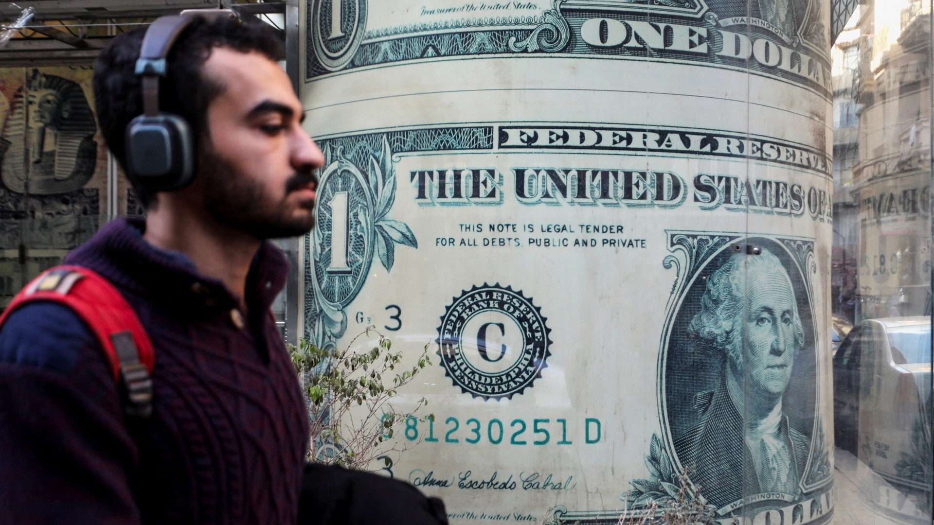 A man walks past a currency exchange point, displaying an image of the U.S. dollar, in Cairo, Egypt, 6 March 2024 (Reuters/Mohamed Abd El Ghany)