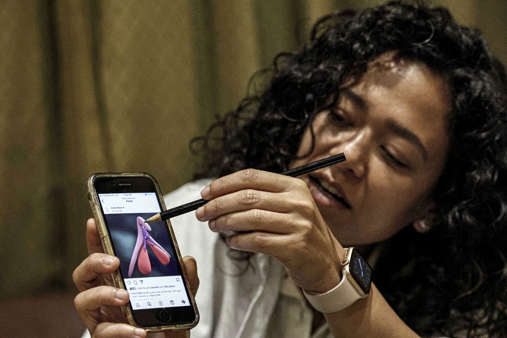 Reham Awwad, médecin, utilise une illustration sur un téléphone pour décrire la procédure de chirurgie de reconstruction clitoridienne à la clinique Restore FGM au Caire (AFP/Khaled Desouki)