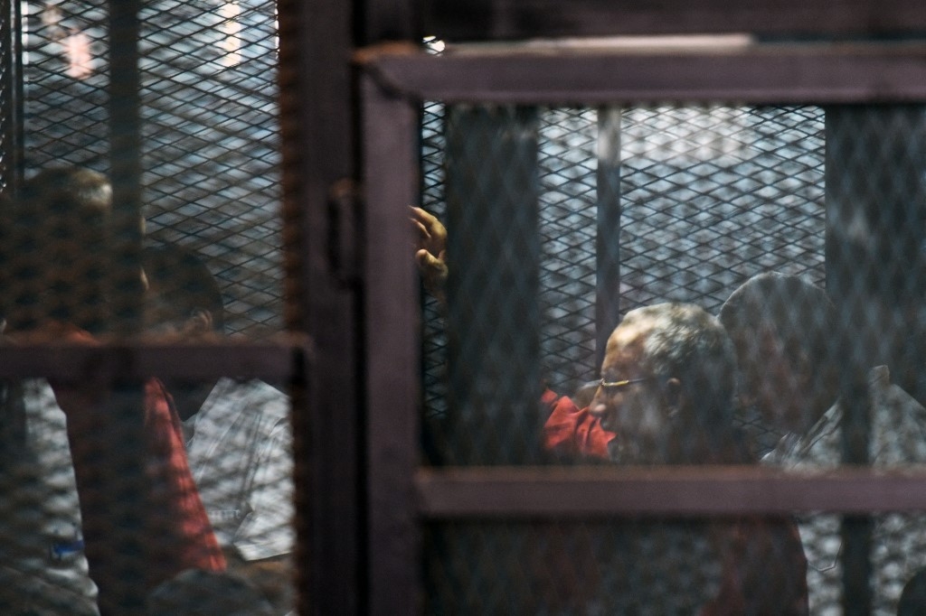 Egyptian Muslim Brotherhood leader Mohamed Badie (2nd-R) stands behind bars during a trial in Cairo in August 2015.